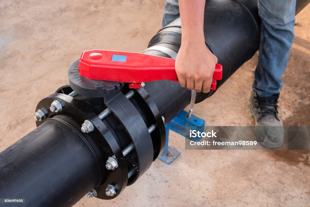 Plumber hand opening butterfly valve in water treatment plant.